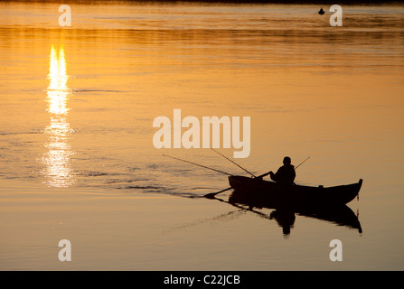 Fisherman trolling from a rowboat / skiff / dinghy at sunset at river Oulujoki Finland Stock Photo