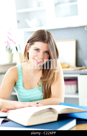 Happy female teenager studying in the kitchen at home Stock Photo