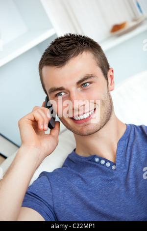 Attractive man sitting on sofa and talking on phone Stock Photo
