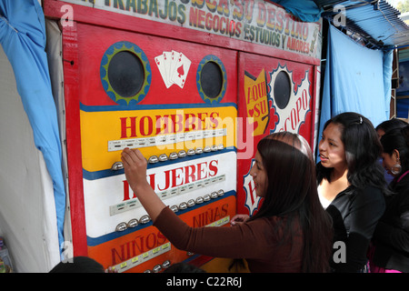 Teenage girl putting token into a fortune telling machine in a fairground , La Paz , Bolivia Stock Photo