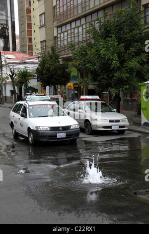 Taxis in street in city centre and water leak caused by a broken pipe / water main, Sopocachi, La Paz , Bolivia Stock Photo