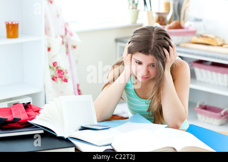 Tired student doing homework sitting in the kitchen Stock Photo