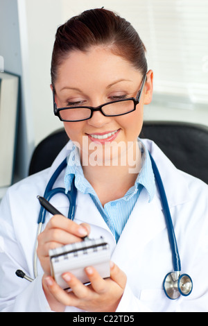 Confident female doctor smiling at the camera holding a notepad Stock Photo