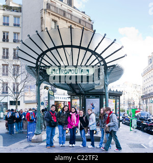 A tour group young people pose for a photo in front of an art-nouveau Metropolitain Metro sign; Paris France. Charles Lupica Stock Photo