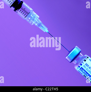 Hypodermic syringe with vial of medication, syringe with vial of medication against purple background, medication being withdrawn  into  a syringe. Stock Photo