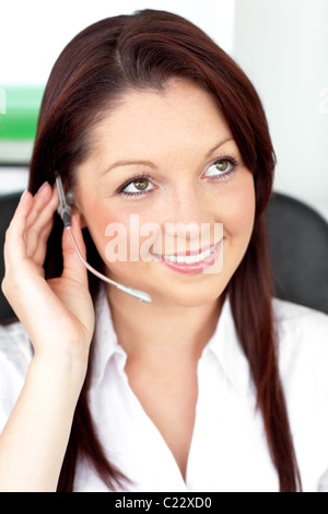 Serious young businesswoman with earpiece in a call center Stock Photo