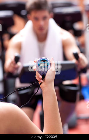 Woman holding a chronometer and man doing physical exercise Stock Photo