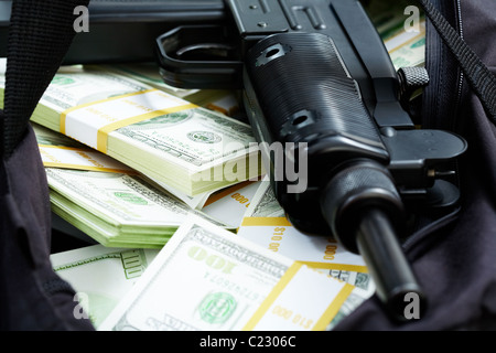 Close-up of black weapon lying on heap of hundred dollar bills Stock Photo