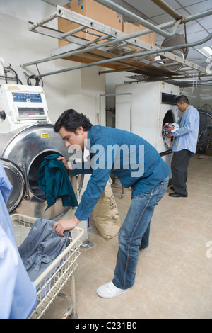 Man loading clothes into the washing machine Stock Photo