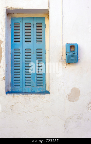 Blue window shutters and a blue electricity meter. Blue windows and shutters is a common sight in the houses of Cyclades. Stock Photo