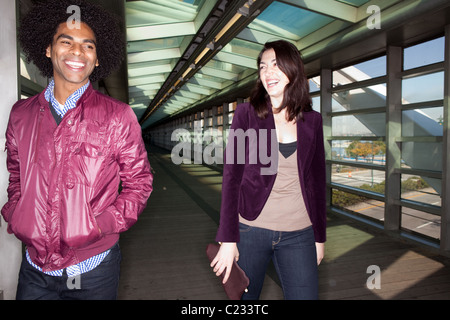 Two young people walking and joking in an urban setting - sharp focus on male Stock Photo