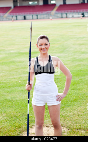 Joyful sporty woman holding a javelin standing in a stadium Stock Photo