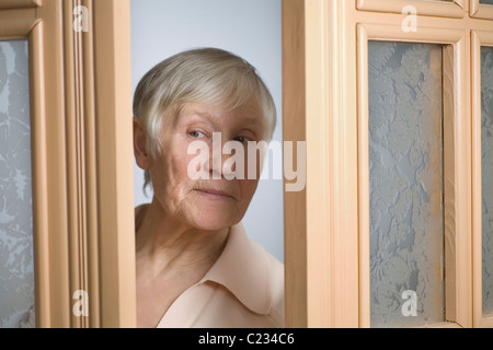 Elderly woman with short grey hair opening front door Stock Photo