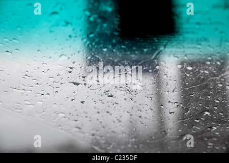 Raindrops on a windshield with blurred road signs in the background. Charles Lupica Stock Photo