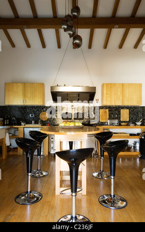 Stefano Giovannoni barstools in modern kitchen with beamed ceiling and Verner Panton lighting Stock Photo
