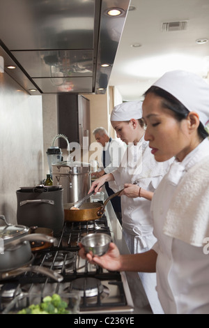 Three chefs work side by side in busy kitchen Stock Photo