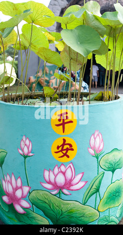 A painted plantar with lotus flower design  and lotus flower plant growing in it at  Haw Par Villa in Singapore Stock Photo