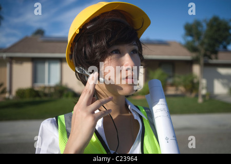 A business lady in working uniform with her hand to a mobile device in her ear Stock Photo