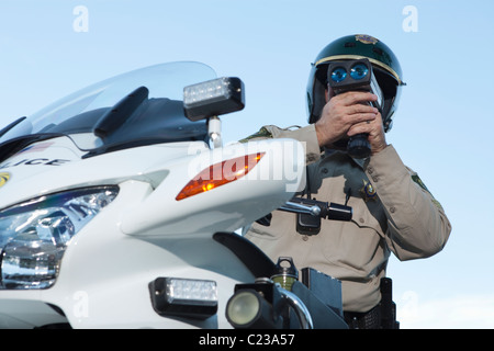 Patrol officer sits on motorcycle looking through pseedometer Stock Photo