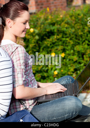 Charming female student using a laptop and sitting behind her boyfriend Stock Photo