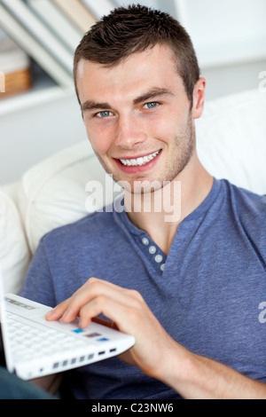 Happy man sitting on the sofa using his laptop Stock Photo