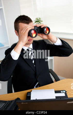 Concentrated young businessman looking through binoluars Stock Photo