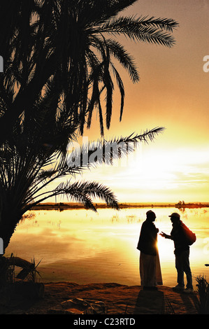 Two Egyptians talking during a sunset over a salt lake in Fatnas Island near the town of Siwa, western desert, Egypt Stock Photo