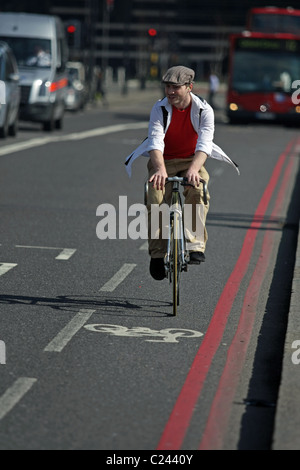 A man with a flat cap riding a bicycle in London, England, on a sunny afternoon Stock Photo