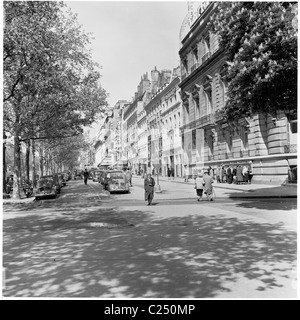 1950s, parked cars of the era in a side-street beside the famous Avenue des Champs-Elysees in Paris, France, with a few Parisians walking past. Stock Photo