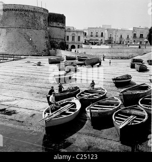 Group of old fishing boats moored on ramp by the old fort, Gallipoli, Italy in this historical picture taken by J. Allan Cash. Stock Photo