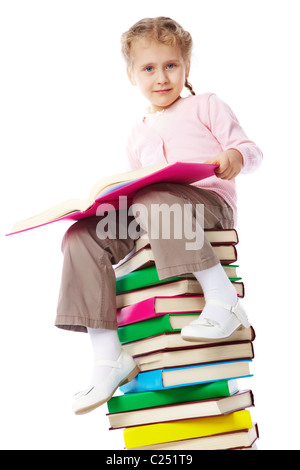 Little girl sitting on stack of books and holding a notebook isolated ...