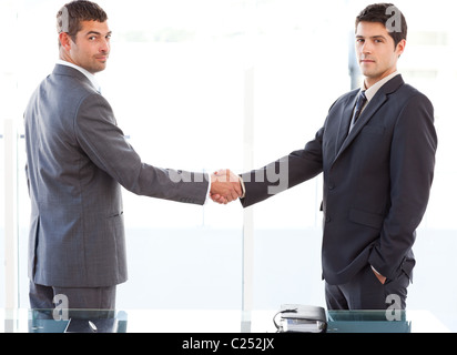 Two charismatic businessmen shaking hands standing in the office Stock Photo