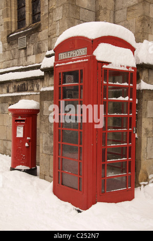 An iconic British red telephone kiosk and a pillar box, standing together in the winter snow, Dorchester High Street. Dorset, England, United Kingdom. Stock Photo