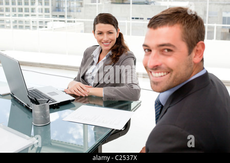 Happy businesspeople working together on a laptop during a meeting Stock Photo