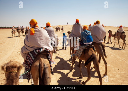 mrazig guide in modern clothing leads british tourists riding