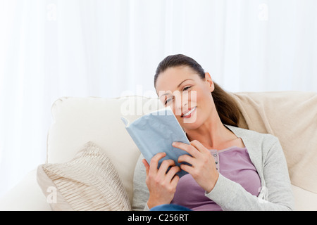Lovely woman reading a romance sitting on the sofa Stock Photo