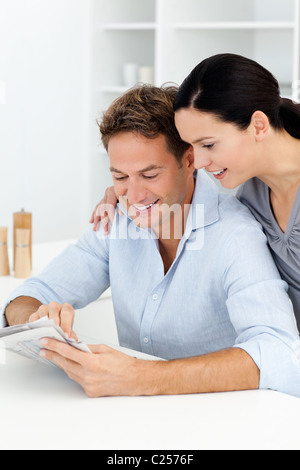 Lovely couple looking at something on the newspaper Lovely couple looking at something on the newspaper