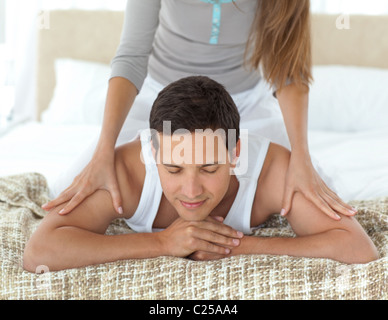 Relaxed man being massaged by his girlfriend on their bed Stock Photo