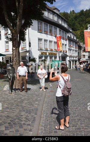 Tourists taking photos by a statue of an old man in the centre of Monschau, Aachen, North Rhine-Westphalia, Germany Stock Photo