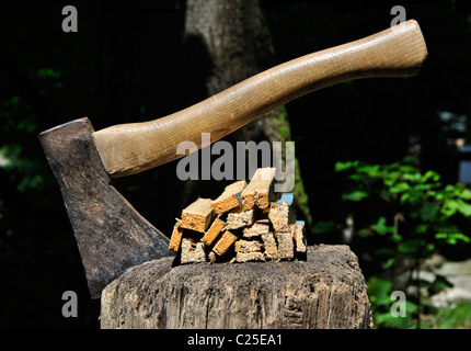 Old Axe stuck in a chopping block and splinters of wood with natural background Stock Photo