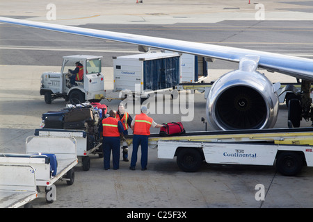 Baggage handlers loading luggage onto a convey into an airplane on the tarmac of New Orleans Airport