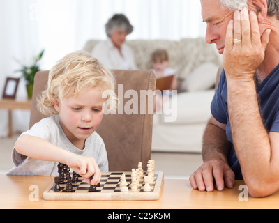 Young boy playing chess with his grandfather Stock Photo