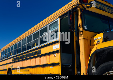 Old rusting abandoned school bus in a junkyard with blue sky in winter Stock Photo