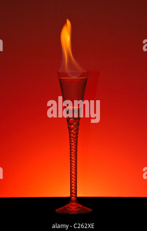 Alcohol burning in beautiful handmade glass with burning red background Stock Photo