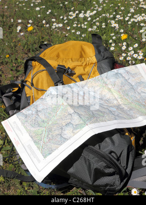 hiking map and backpack lying on a flower meadow, concept for: concept for exploring nature, walking, hiking,being active, Stock Photo