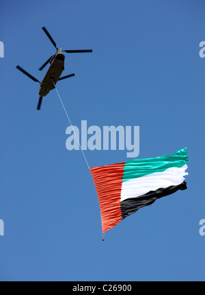 Military helicopter carries the national flag of the United Arab Emirates over the capital  Abu Dhabi. During a military show. Stock Photo
