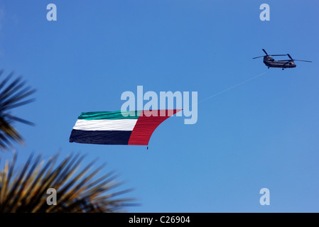 Military helicopter carries the national flag of the United Arab Emirates over the capital  Abu Dhabi. During a military show. Stock Photo