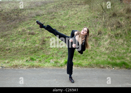 Young Caucasian woman doing a tae kwon do kick outside, taken in Emersons Green, Bristol Stock Photo