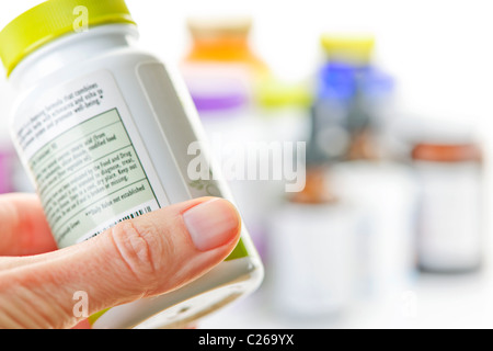 Hand holding medicine bottle to read label Stock Photo