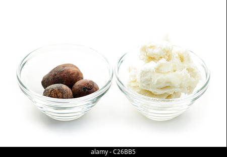 Shea butter and nuts in glass bowls isolated on white Stock Photo